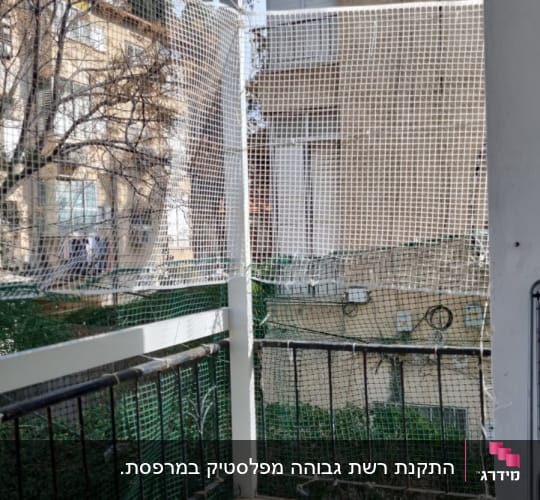 רשת בטיחות מותקנת על מרפסת עם מעקה ברזל